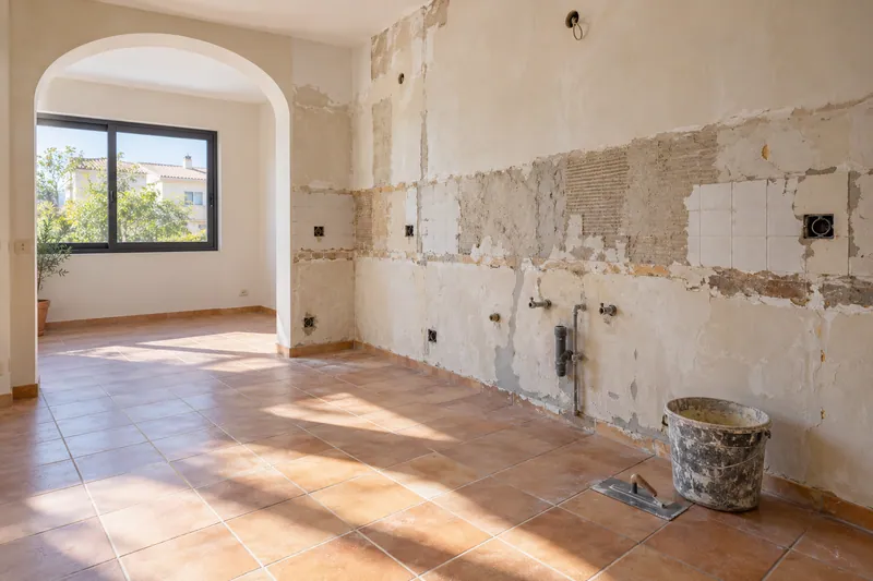 Visualización conceptual IA: Cocina sin muebles con paredes en preparación y zonas de enlucido.